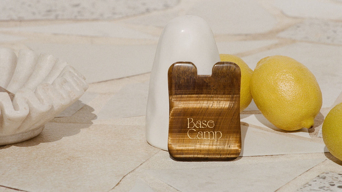 Base Camp Beauty timber  Gua Sha with three lemons in the background, and a stone shell dish.