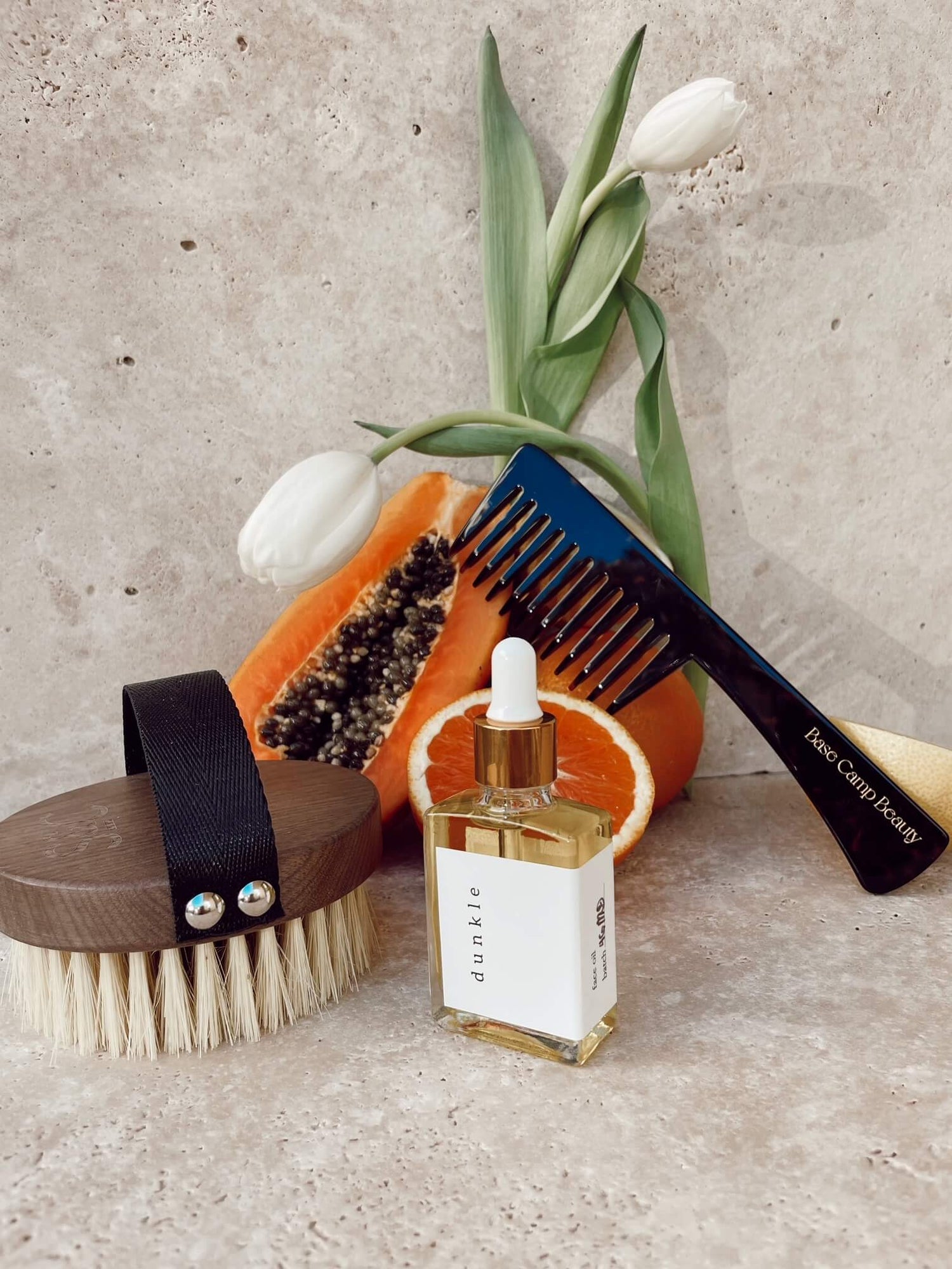 A selection of self-care products for your beauty rituals. The products are styled with fruit and white tulips.