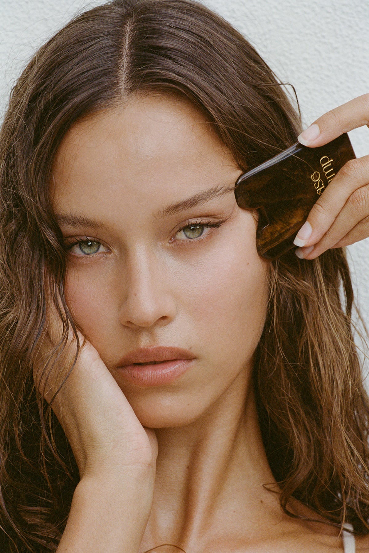 A beautiful woman using the Base Camp Beauty gua sha as part of her self-care ritual.