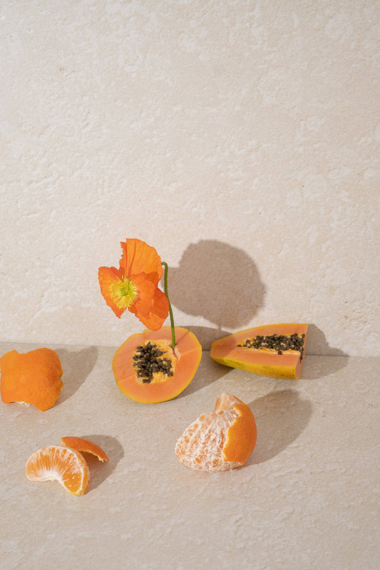 An orange flower with cut papaya and a peeled mandarin.