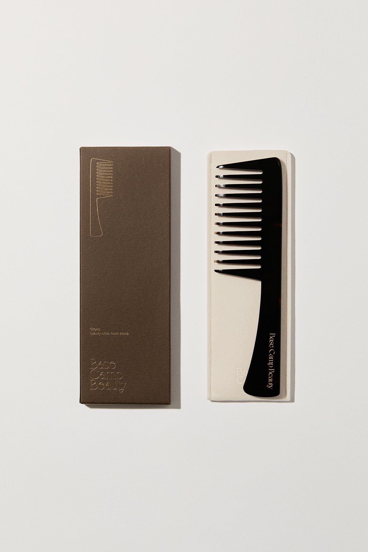 Flatlay of Base Camp Beauty tortoise comb, storage sleeve and brown Base Camp Beauty box.