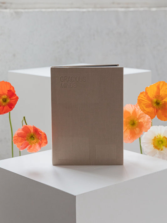 beige coloured journal sitting on a white plinth with poppies either side
